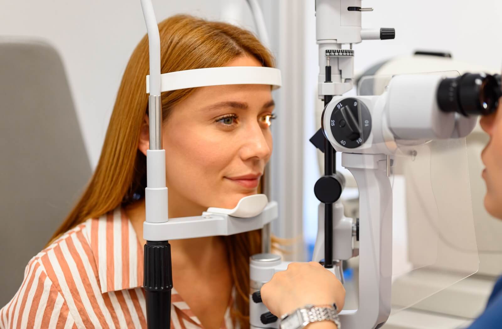 Woman having a comprehensive eye exam using a slit lamp.